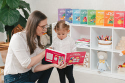 Bilingual mother reads a bilingual musical book with her bilingual toddler, practicing new Spanish words with a Spanish song. 